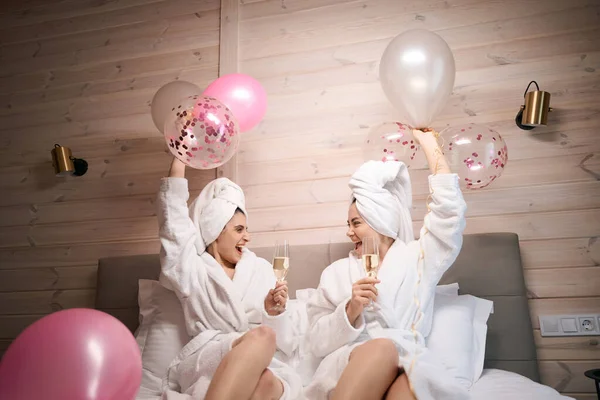 Balonlu Şampanyalı Iki Neşeli Kadın Otel Odasında Büyük Bir Yatakta — Stok fotoğraf