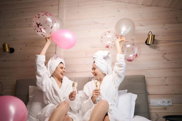Zwei Überglückliche Weibchen Mit Luftballons Und Champagnergläsern Sitzen Auf Einem — Stockfoto