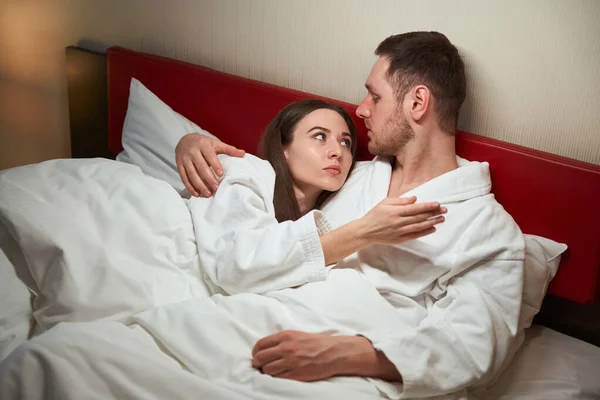 Erkek Otel Odasında Yatakta Omzunda Uzanan Ciddi Bayan Arkadaşına Sarılıyor — Stok fotoğraf
