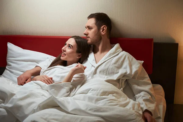 年轻的女人们躺在床上 躺在沉思的伴侣的怀里 笑得很开心 — 图库照片