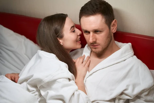 Gülümseyen Kadın Yatakta Yatarken Sevgili Adamın Kulağına Bir Şeyler Fısıldıyor — Stok fotoğraf