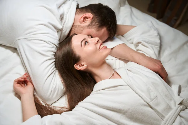 在酒店房间里 快乐的女性躺在伴侣的旁边 — 图库照片