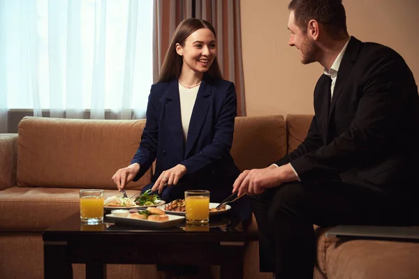 若い男女がソファーに座って朝食をとり モーテルルームでお互いを見つめ合った — ストック写真
