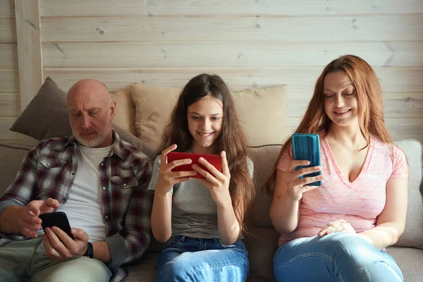 Jongedame Haar Ouders Zitten Bank Woonkamer Met Mobieltjes Hun Handen — Stockfoto