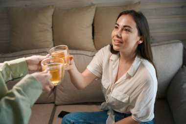 Kadınlar kanepede otururken ellerinde bir fincan çay tutuyorlar.
