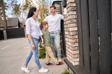 Genç ebeveynler ve oğulları yeni evlerinin bölgesine girerler.