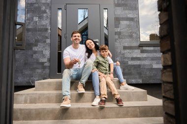 Evin girişinin yanında üç aile üyesi oturuyor.