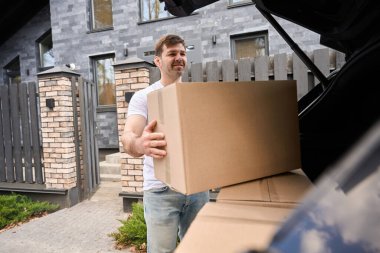 Adam yeni bir eve taşınırken kutuyu bagajdan çıkarır.
