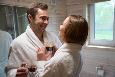 Gülümseyen adam ve kadın ellerinde kahveyle birbirlerine bakıyorlar.