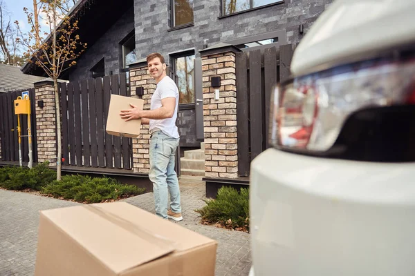 Guy in light clothes carries boxes while moving to a new house