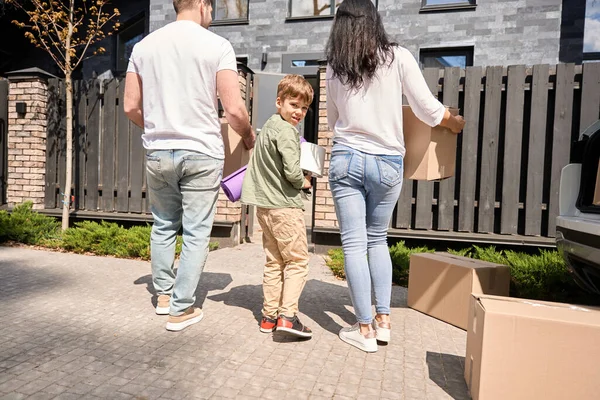 彼らの顔に笑顔で新しい家に箱を運ぶコーカサス家族 — ストック写真