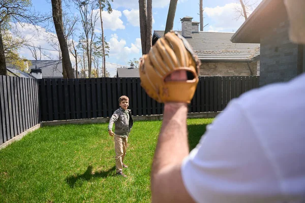 Caucasian man with a baseball glove plays with a child on his territory