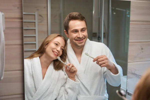 年轻夫妇看着镜子 手里拿着牙刷 — 图库照片