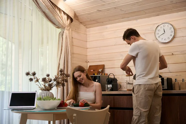 一对年轻夫妇在餐桌旁的一幢乡间房子里准备早餐 — 图库照片