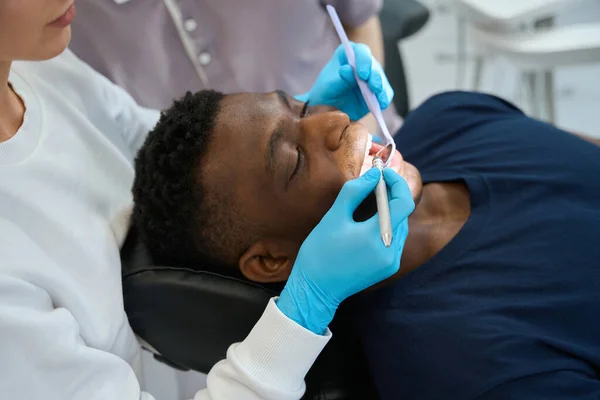 手の内腔の健康をチェックするための特別なツールを握っている女性の物理学者は 病気の探査機で各歯に触れ 口の鏡を見ます — ストック写真