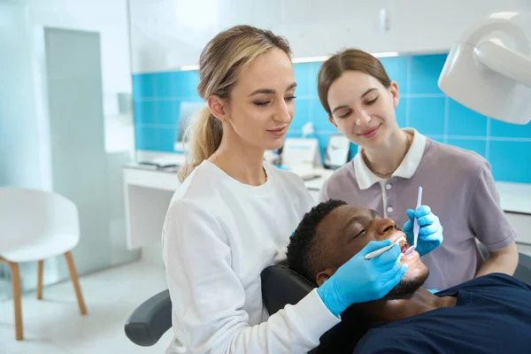 在非裔美国人口腔检查 牙科问题预防 保健期间协助女牙医的年轻护士 — 图库照片