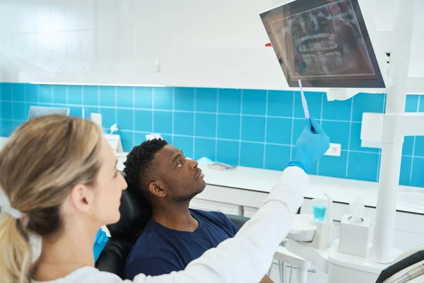 アフリカ系アメリカ人患者を顎のX線画像でデジタルスクリーンに注目し 問題のある歯を示す — ストック写真