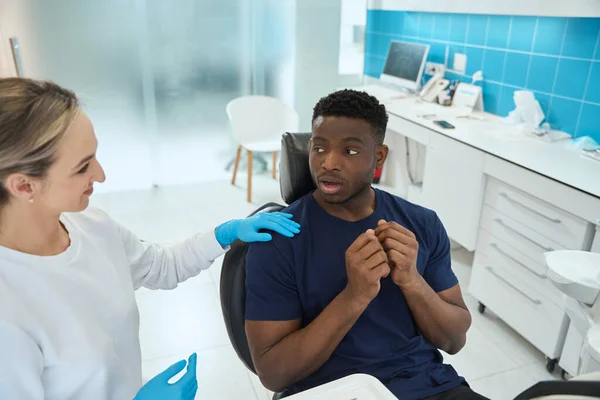 笑顔の女性歯医者落ち着く怖いアフリカ系アメリカ人男性 医師の診察に来て歯科椅子に座って — ストック写真