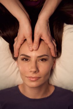 Masöz alnındaki akupuanları uyarırken sakin kadının sırtüstü yatışının üst görüntüsü.