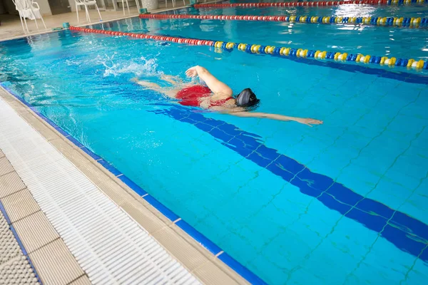 身穿泳衣的白人女子在水中练习自由泳的背景图 — 图库照片