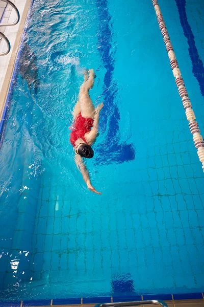 泳衣和泳帽的女运动员在游泳池里仰泳的头像 — 图库照片