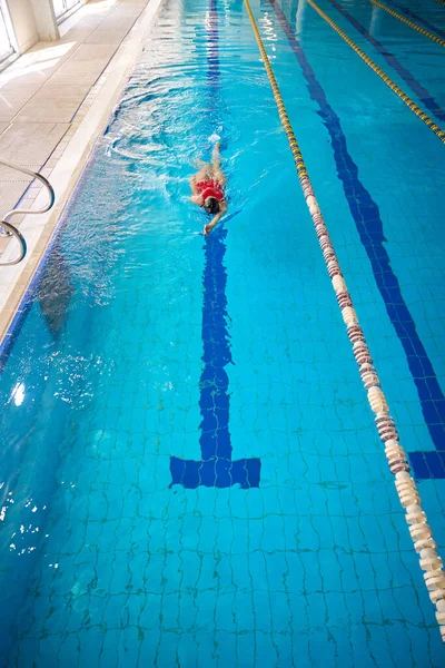水中バックストロークをする水泳帽子と水着のスポーツウーマントップビュー — ストック写真