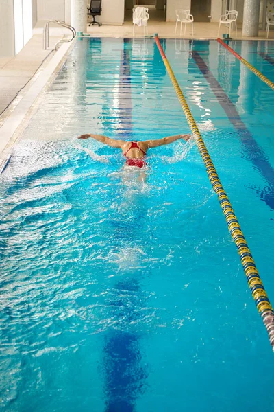 水中バタフライストロークをする水着のコーカサススポーツ選手のバックビュー — ストック写真