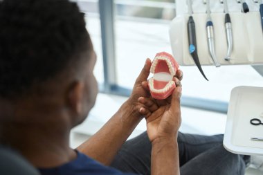 Estetik stomatoloji kliniğinin erkek müşterisi çenesinin 3D modeline bakıyor, diş teli taktıktan sonra dişlerini düzleştirmenin iyi bir örneği