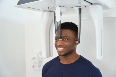 Hastanedeki hasta bilgisayarlı tomografi cihazının yanında duruyor. Kafatası ve dişlerin tomografik görüntüsü