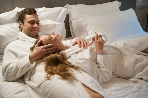 Couple Heureux Amoureux Dans Des Peignoirs Couchés Dans Lit Confortable — Photo
