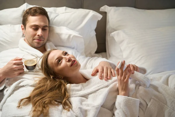 Attractive Couple Love Lying Bed Bathrobes Man Drinking Fresh Brewed — Stock Photo, Image