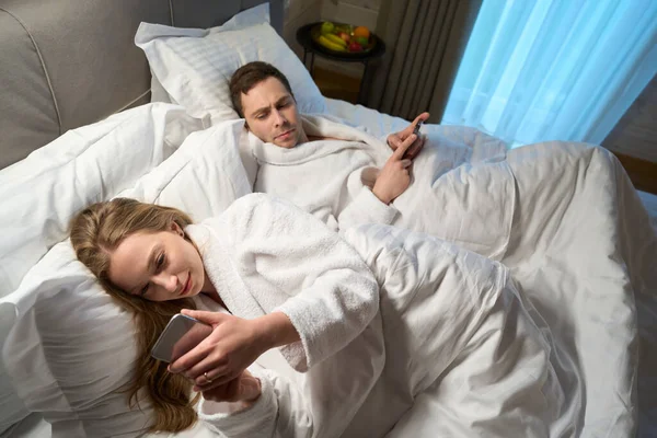Couple Lying Bed Apart Cellphones Anxious Husband Looking His Wife — Stock Photo, Image