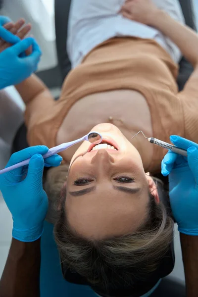 Sandalyeye Oturmuş Gülümseyen Hasta Koruyucu Eldivenli Doktor Diş Aynası Tutuyor — Stok fotoğraf