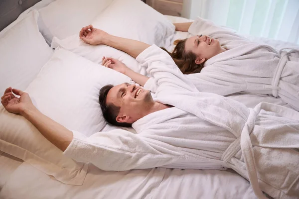 Smiling Woman Man White Bathrobes Laying Bed Hands — Stock Photo, Image