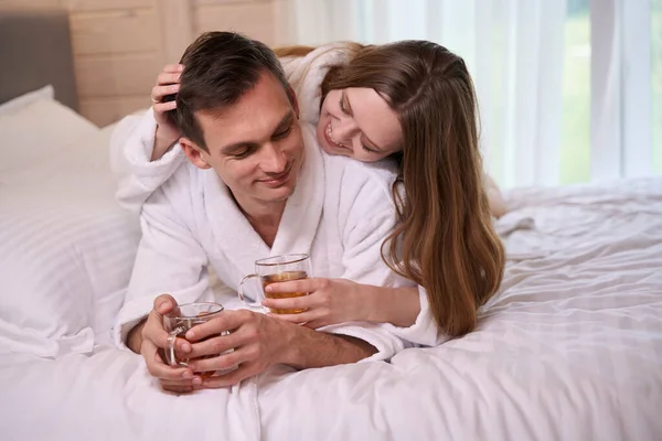 Happy Woman Lying Smiling Man Back Wearing Dressing Gowns While — Stock Photo, Image