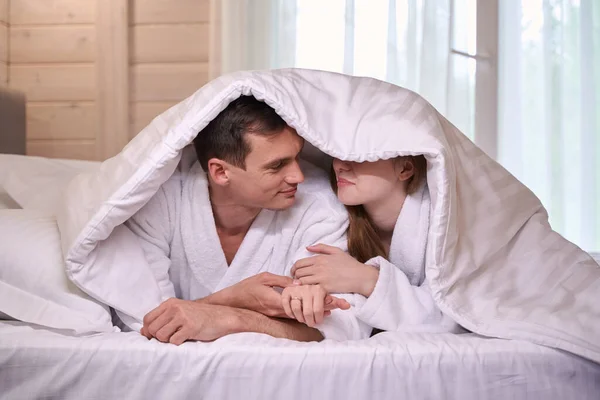 Happy Couple Bathrobes Lying Bed Heads Covered Blanket — Stock Photo, Image