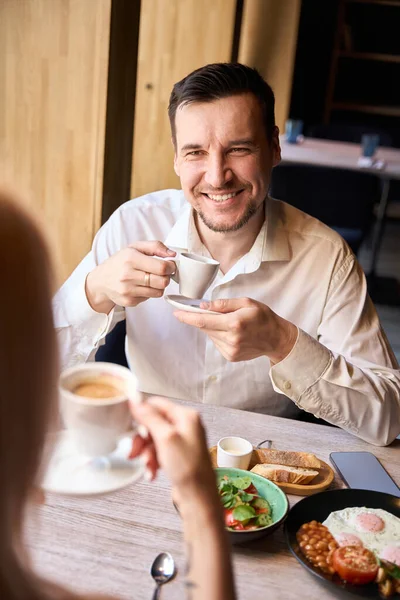 Businessman calling woman on date to cafe, couple having breakfast and drinking fresh brewed coffee, communicating with each other, back-view