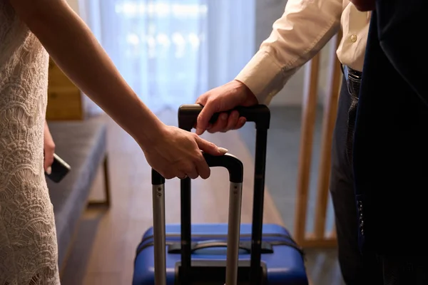 Close-up man in business suit and woman in elegant white dress standing in hotel room holding suitcases, entering or leaving hotel, vacation time