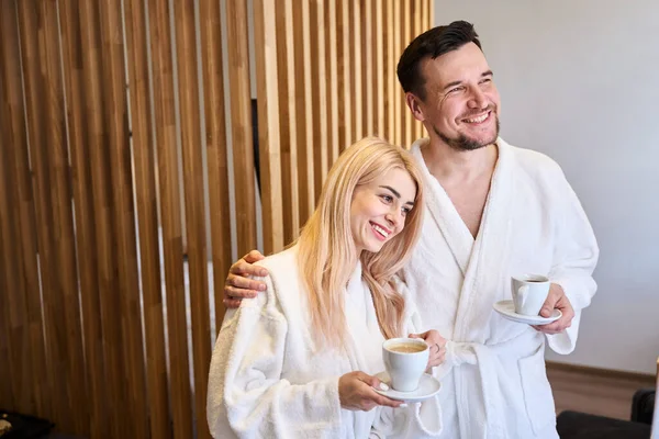 一对快乐的夫妇在度假的早上尽情享受 穿着洁白柔软的浴衣喝咖啡 在温泉酒店度假胜地休息和放松 — 图库照片