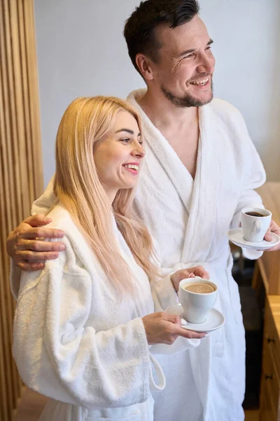 美丽动人的情侣们 穿着浴衣 笑着喝咖啡 看风景 一起享受周末的娱乐 — 图库照片