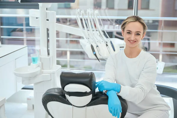 Uśmiechnięta Kobieta Rękawiczkach Ochronnych Siedząca Krześle Przygotowująca Się Pracy Stomatologii — Zdjęcie stockowe