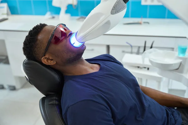 Mężczyzna Okularach Siedzący Fotelu Poddany Zabiegowi Wybielania Zębów Stomatologii — Zdjęcie stockowe