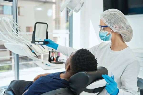 Dentiste Uniforme Chapeau Protection Debout Près Homme Tenant Miroir Parler — Photo