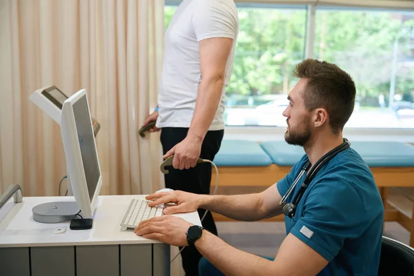 Doctor Seated Desk Looking Computer Display While His Client Undergoing — Stock Photo, Image