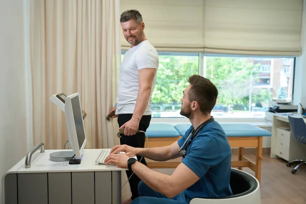 Lékař Sedící Stolem Před Počítačem Dívající Svého Pacienta Během Procedury — Stock fotografie