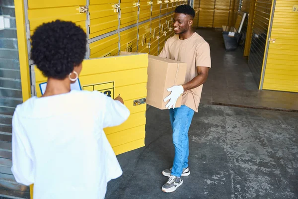 Young Man Loads Cardboard Box Storage Unit Next Woman Manager — Stock Photo, Image