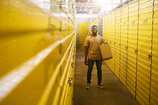 Афроамериканец Джинсах Стоит Картонной Коробкой Рядом Контейнерами Хранения Вещей Ячейки — стоковое фото