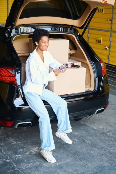African American Female Talks Phone Sitting Edge Trunk Lot Cardboard — Stock Photo, Image