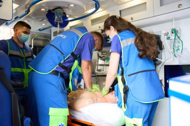 Ambulansta bir hastanın hayata döndürülmesi, kalp masajı yapan sağlık görevlileri...