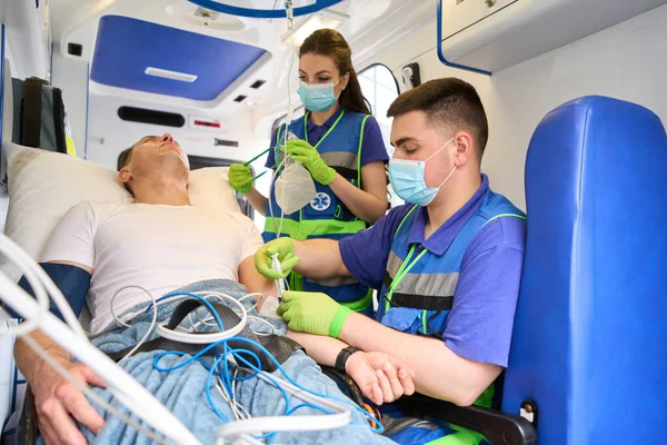 Mobile medical team connects a patient to a drip in an ambulance